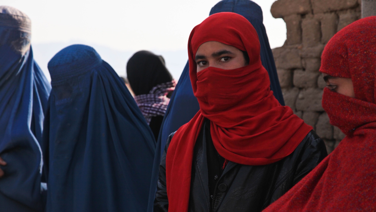 Donne in Afghanistan con burqa blu e chador rossi